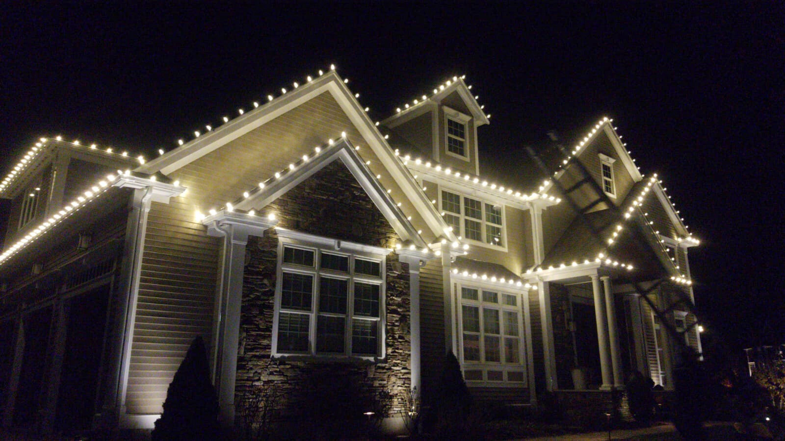 Permanent LED roofline lighting on an upscale New Hampshire home at dusk
